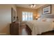 Bedroom features plantation shutters, wood-look flooring, and a dresser with a mirror at 21857 N Gibson Dr, Maricopa, AZ 85139