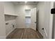 Laundry room with wood-look tile floor, white walls, storage shelf and door to walk-in closet at 22961 E Twin Acres Dr, Queen Creek, AZ 85142