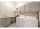 Bright laundry room with washer, dryer, sink, countertop, and storage cabinets at 2643 E San Ricardo Trl, Casa Grande, AZ 85194