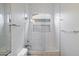White tiled bathroom featuring a tub, and a glass shower door and a view through the window at 4088 E Comstock Dr, Gilbert, AZ 85296