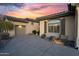 View of a clean garage and patterned driveway with desert landscaping and a colorful sunset at 41711 N Pinion Hills Ct, Anthem, AZ 85086