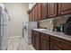 Functional laundry room with modern appliances, wood cabinets, and laminate flooring at 41711 N Pinion Hills Ct, Anthem, AZ 85086