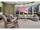 Comfortable living room with curved windows overlooking the sunset and mountain views at 41711 N Pinion Hills Ct, Anthem, AZ 85086