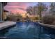Inviting pool with waterfall feature and lush desert landscaping at twilight at 41711 N Pinion Hills Ct, Anthem, AZ 85086