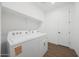 Bright laundry room with a Whirlpool washer and dryer, open shelving, and white walls at 4238 W Brenley Dr, San Tan Valley, AZ 85144