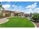 Expansive backyard with lush green lawn, patio, desert landscaping, and outdoor lighting at 5334 S Parkwood --, Mesa, AZ 85212