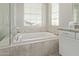 Elegant bathtub with tiled surround, large window, and adjacent granite countertop at 10054 E Bell Rd, Scottsdale, AZ 85260