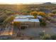 Aerial view of a home surrounded by desert landscape with a white roof, desert landscaping, and mature trees at 10767 E Santa Fe Trl, Scottsdale, AZ 85262