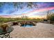 Inviting backyard spa with stacked stone waterfall feature, built-in seating, and desert sunset views at 10767 E Santa Fe Trl, Scottsdale, AZ 85262