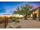 Serene backyard showcasing a desert landscape, mature tree, and a glimpse of the Arizona sunset at 10767 E Santa Fe Trl, Scottsdale, AZ 85262