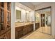 Double sink vanity in bathroom with wood cabinets, mirrors, and view to glass shower wall at 10767 E Santa Fe Trl, Scottsdale, AZ 85262