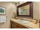 Bathroom vanity with dark wood cabinets, neutral granite countertop, and a framed mirror on the wall at 10767 E Santa Fe Trl, Scottsdale, AZ 85262