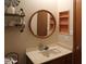 Charming bathroom features stylish round mirror, decorative shelves, and built-in storage at 11406 W Montana Ave, Youngtown, AZ 85363