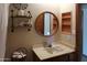 Charming bathroom features stylish round mirror, decorative shelves, and built-in storage at 11406 W Montana Ave, Youngtown, AZ 85363