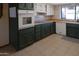 A view of the kitchen featuring tile floors, dark green cabinets, and stainless steel appliances at 11406 W Montana Ave, Youngtown, AZ 85363