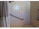 Shower with tiled walls, a shower curtain, a built-in seat, and grab bars for accessibility at 11406 W Montana Ave, Youngtown, AZ 85363