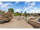 Desert-landscaped backyard features rocks, flowering bushes, gravel, and an outdoor retaining wall at 15542 W Cypress Point Dr, Surprise, AZ 85374