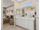 A bathroom with a dual sink vanity, a framed mirror, and a view into the adjacent bedroom at 15542 W Cypress Point Dr, Surprise, AZ 85374