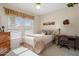 Well-lit bedroom with a queen bed, dresser, desk, and large windows covered by white blinds at 15542 W Cypress Point Dr, Surprise, AZ 85374