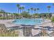 Community pool with lounge chairs, umbrellas, lush trees and convenient access for residents at 17143 W Oberlin Way, Surprise, AZ 85387