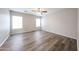 Spacious bedroom with wood-look floors, ceiling fan, and bright, natural lighting from two windows at 22473 W Woodlands Ave, Buckeye, AZ 85326