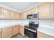 A modern kitchen with stainless steel appliances, light wood cabinets, and quartz countertops at 22473 W Woodlands Ave, Buckeye, AZ 85326