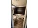 Stylish half bathroom with a pedestal sink, dark accent wall, and wood-look flooring at 25035 N 63Rd Dr, Phoenix, AZ 85083