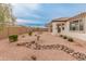 An open backyard features desert landscaping, including rock beds, trees and a covered patio at 3287 N 197Th Ln, Buckeye, AZ 85396