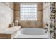 Bathroom featuring a soaking tub with decorative tile and a glass block window at 3441 S Camellia Pl, Chandler, AZ 85248