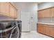 Well-lit laundry room features wooden cabinetry above washer and dryer at 3441 S Camellia Pl, Chandler, AZ 85248