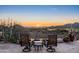 Outdoor seating area with a stone patio, fire pit, and scenic mountain views at sunset at 40947 N 107Th Pl, Scottsdale, AZ 85262