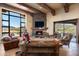 Comfortable living room with stone fireplace, wood beams, and a view of the pool and desert landscape at 40947 N 107Th Pl, Scottsdale, AZ 85262