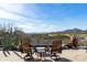 A stone patio is furnished with comfortable chairs, table, and desert mountain views at 40947 N 107Th Pl, Scottsdale, AZ 85262