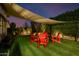 Backyard with artificial turf, a sunshade and red Adirondack chairs in conversation arrangement at 4191 S Emerald Dr, Chandler, AZ 85249