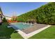 A modern pool and deck is surrounded by lush privacy hedges and green artificial turf and an adjacent lounge area at 4191 S Emerald Dr, Chandler, AZ 85249