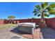 Backyard showcasing a hot tub with surrounding desert landscaping and a tall palm tree at 42297 W Lunar St, Maricopa, AZ 85138