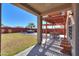 Covered patio with stylish pergola, seating, and a view of the green lawn and mature trees at 42297 W Lunar St, Maricopa, AZ 85138