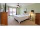 Cozy main bedroom with carpeted floors, featuring a ceiling fan and a large window for natural light at 42297 W Lunar St, Maricopa, AZ 85138