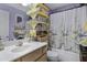 Charming bathroom features a single sink vanity, decorative shelves, and a shower-tub combo with patterned curtain at 5848 W Gelding Dr, Glendale, AZ 85306