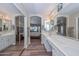 Bathroom featuring double sinks, vanity, large mirror, and view of the primary bedroom at 8444 W Rockwood Dr, Peoria, AZ 85382