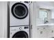 Modern laundry room with stacked washer and dryer, adjacent to a kitchen area with a farmhouse sink at 8556 E Pecos Ln, Scottsdale, AZ 85250