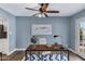 Stylish home office with wood-look tile floors, a modern ceiling fan, and a bright blue accent wall at 8556 E Pecos Ln, Scottsdale, AZ 85250