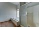 Bathroom with tiled tub, glass shower, window and wood-look flooring at 934 E Carlise Rd, Phoenix, AZ 85086