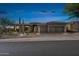 Beautifully landscaped single-story home featuring a three-car garage, desert plants, and illuminated entry at dusk at 10951 E Mirasol Cir, Scottsdale, AZ 85255