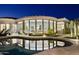 Backyard pool reflecting the house, featuring desert landscaping, patio, and large windows at 10951 E Mirasol Cir, Scottsdale, AZ 85255