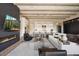 Open-concept living space with fireplace, TV, wood beam ceiling, and view of the modern kitchen and dining area at 12315 E Black Rock Rd, Scottsdale, AZ 85255