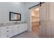 Bright bathroom featuring white cabinets, granite countertops, and a rustic sliding door to the walk-in closet at 12770 N 145Th Way, Scottsdale, AZ 85259