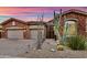 Charming desert home with a stone exterior, multi-car garage and desert landscaping under a dramatic sunset at 12770 N 145Th Way, Scottsdale, AZ 85259