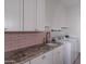 Well-organized laundry room features granite counters, pink backsplash, and modern appliances at 12770 N 145Th Way, Scottsdale, AZ 85259