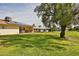 Sprawling backyard with green lawn, mature trees, and covered patio at 13410 N Cedar Dr, Sun City, AZ 85351